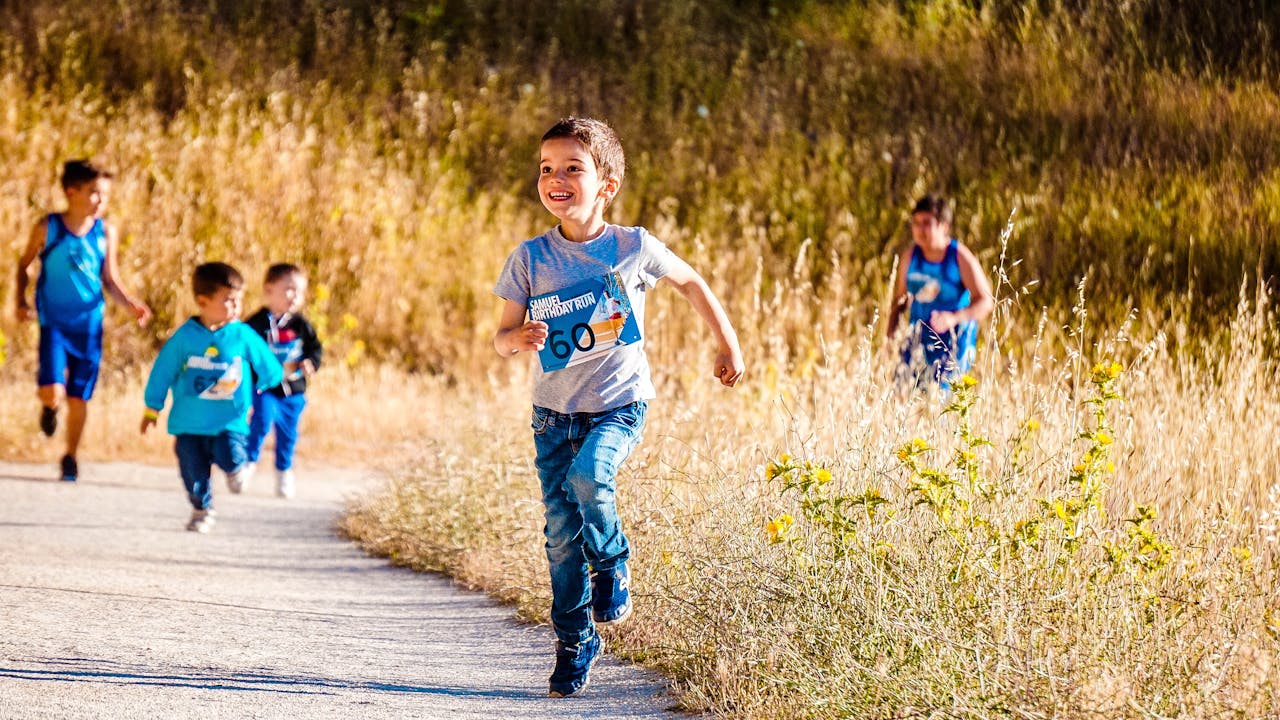 Children joyfully running in a park during a cheerful outdoor race event.