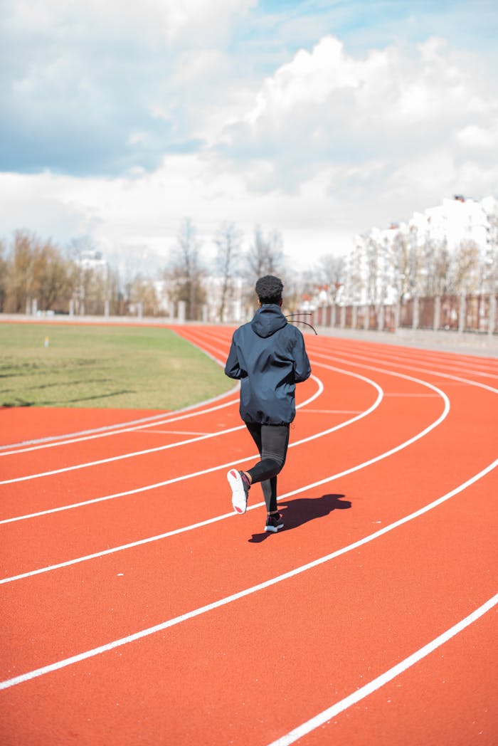 A woman runner exercising on a track outdoors during the day. Athletic training concept.